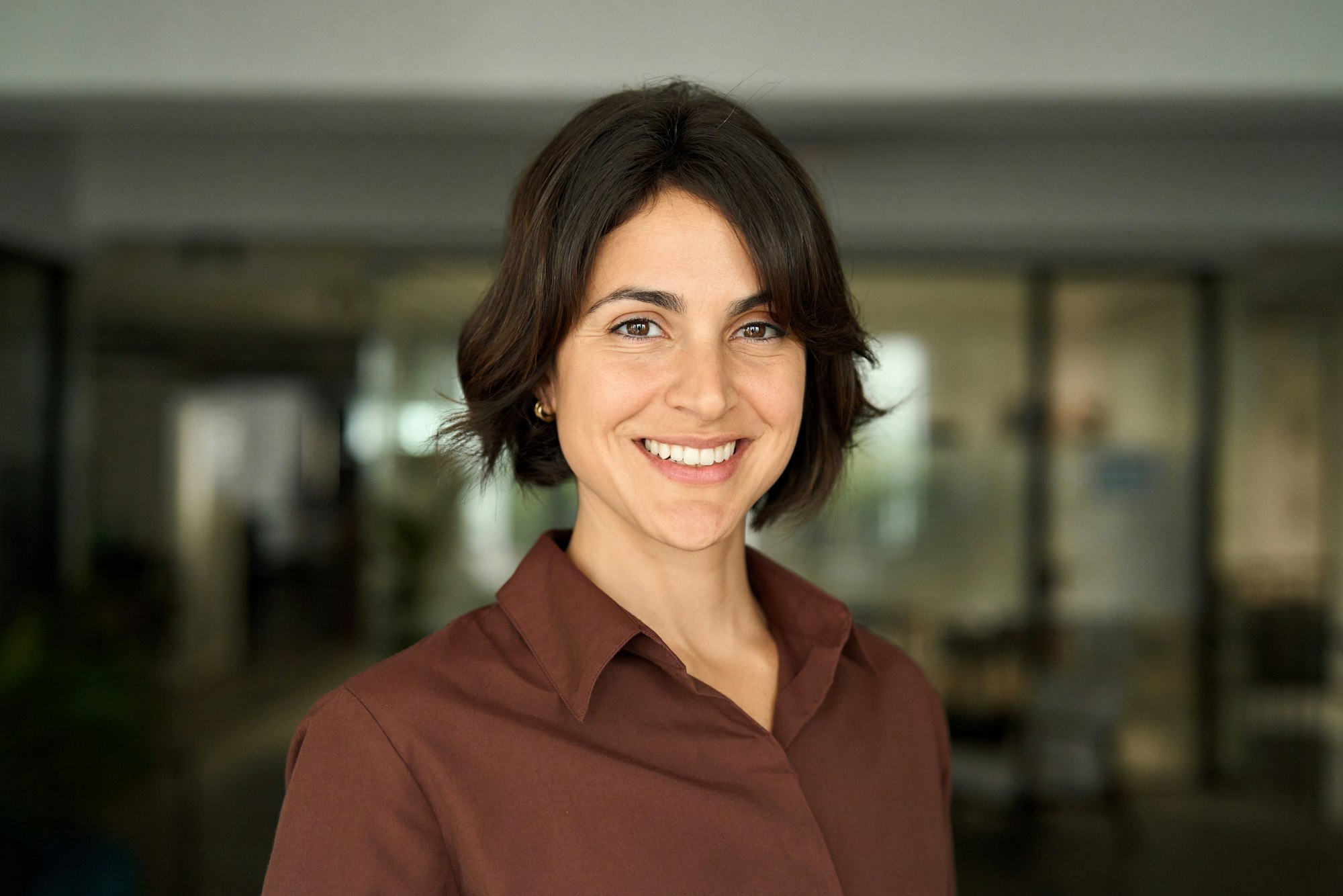 Headshot close up face portrait of young happy smiling Hispanic businesswoman.